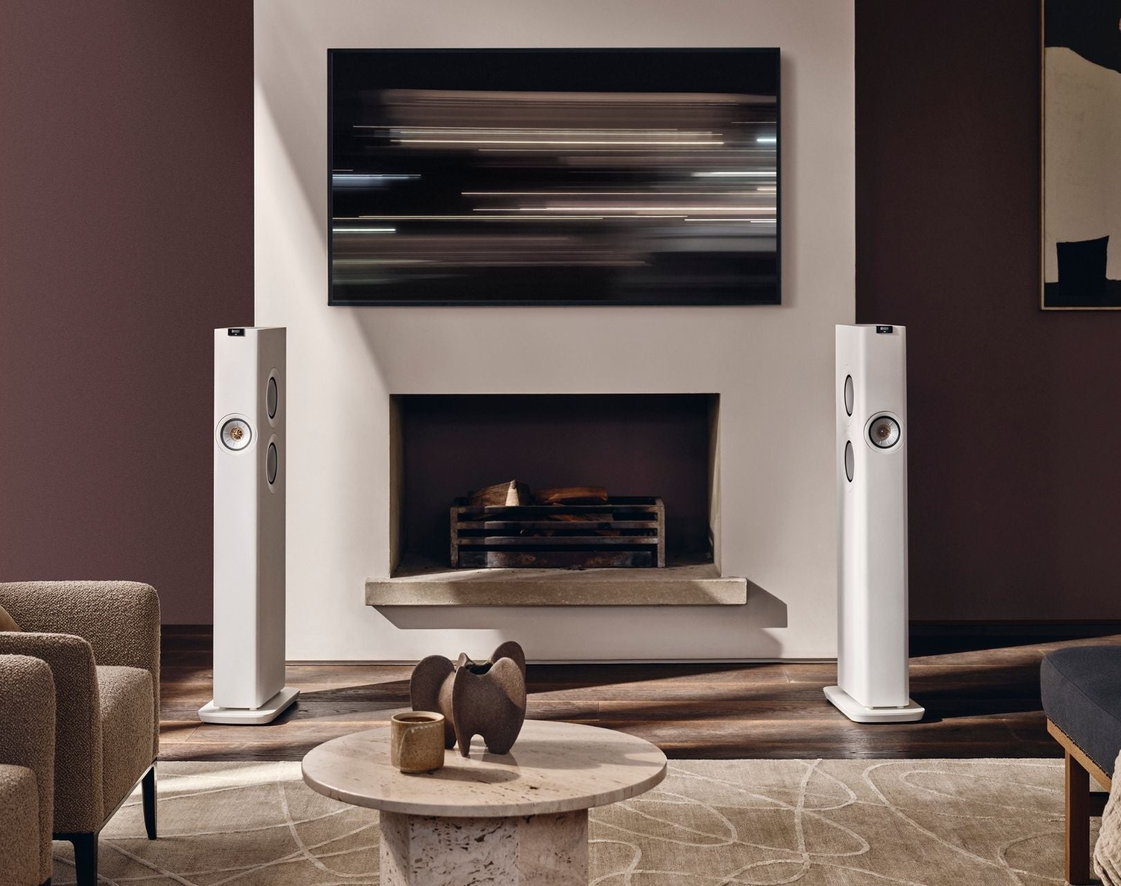 Living room with white floor-standing LS60 speakers, a fireplace, and a television.