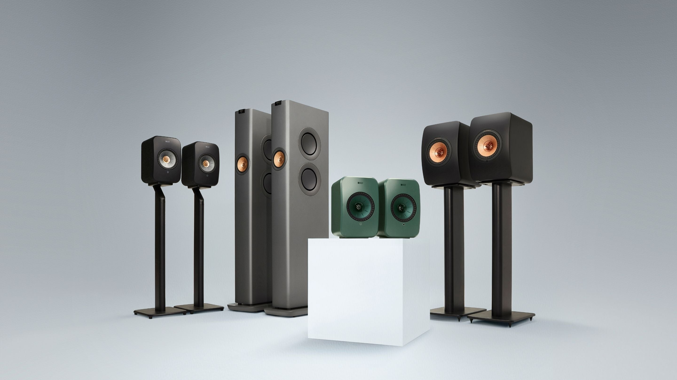 Set of KEF LS Wireless speakers on stands against a grey background
